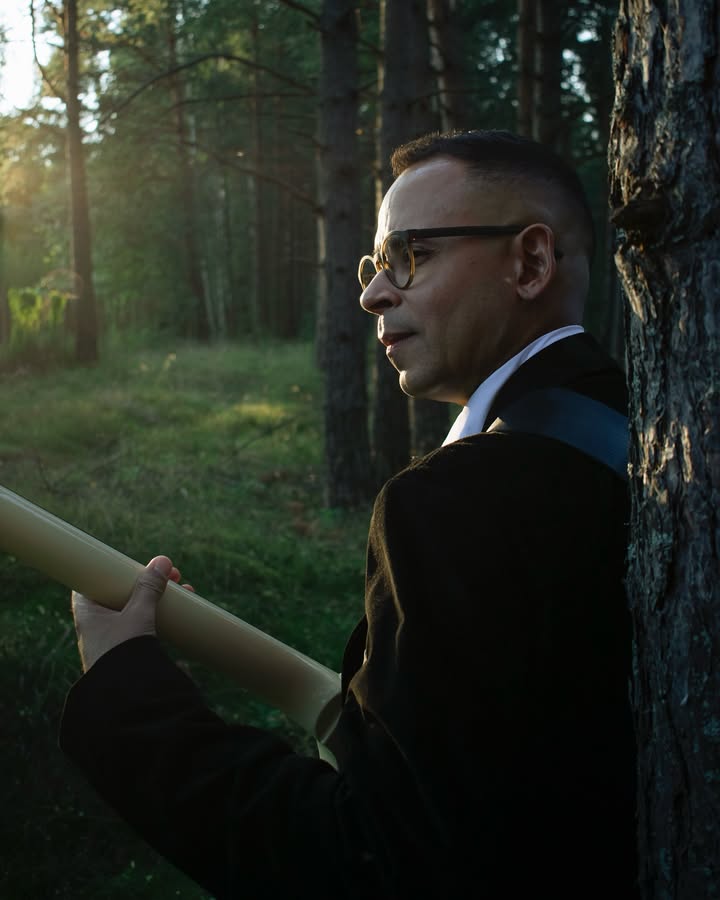 Klienta portrets mežā ar tūbu rokā — siltas saulrieta gaismas profils starp priedēm